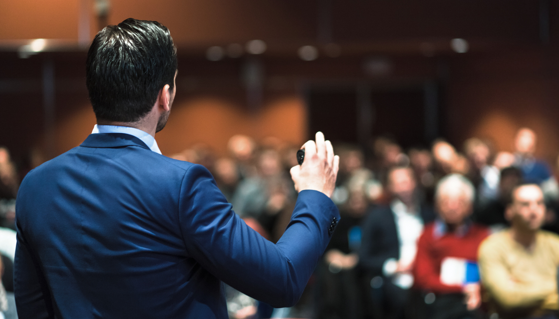 a man speaking in front of crowd of people